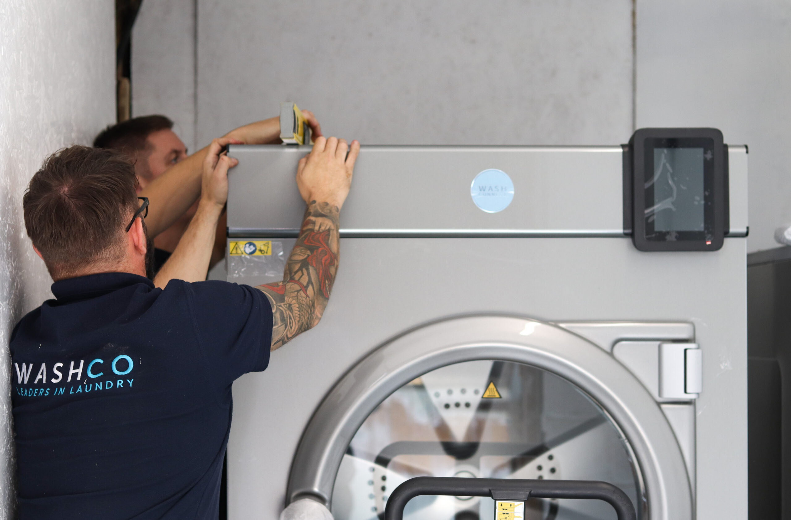 Two WASHCO installers installing a WASHCONNECT machine.