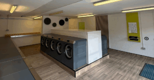 A WASHPOINT laundry room with washing machines. White walls with green accents and wooden styled floors.